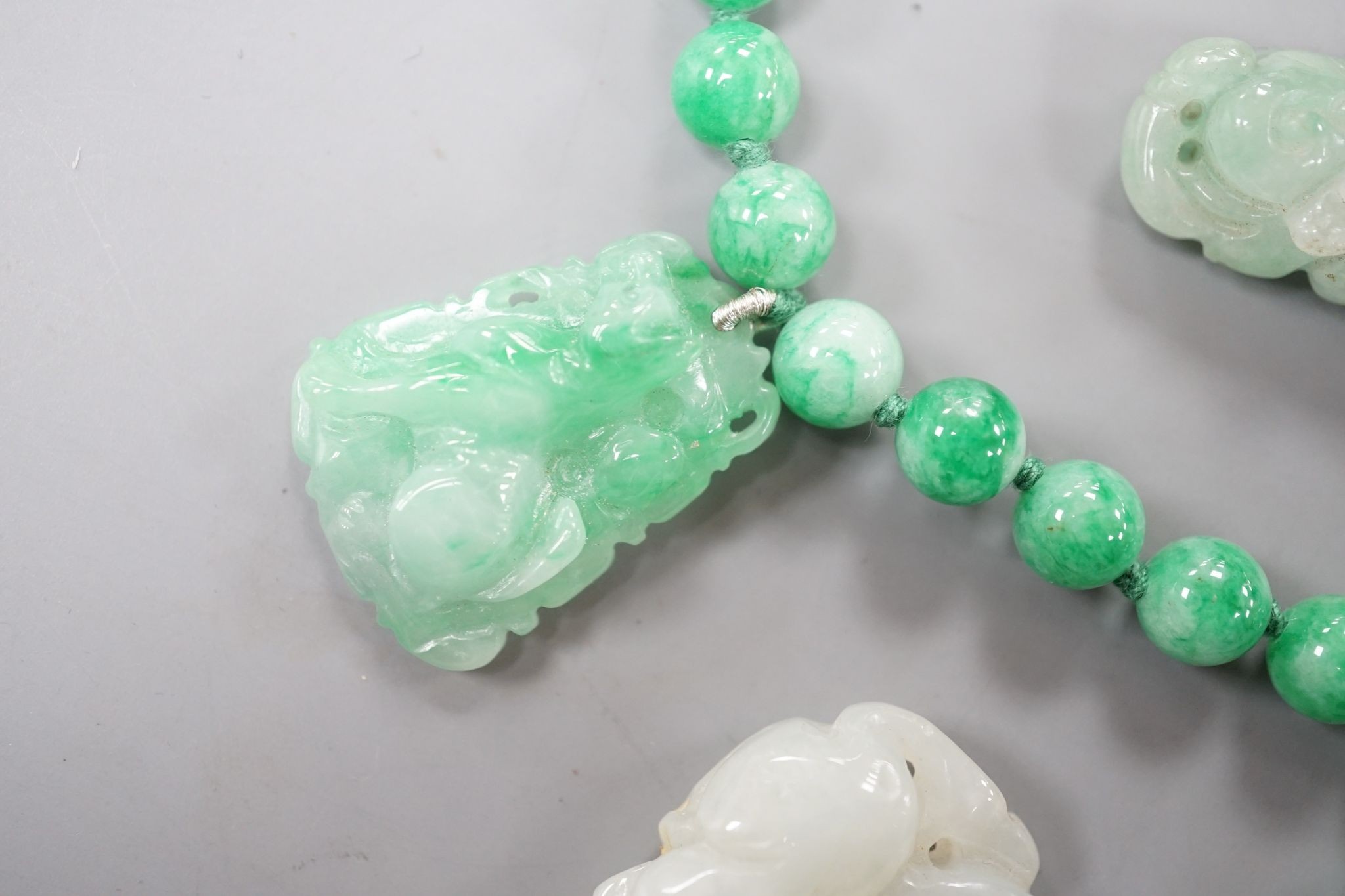 A jade bead necklace hung with three jade carvings, 49cm and three other jade carvings.